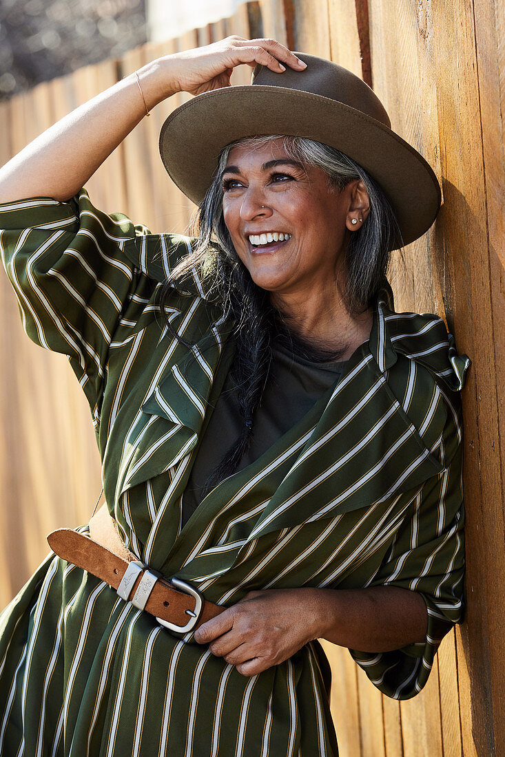 A grey-haired woman wearing a striped dress and a hat