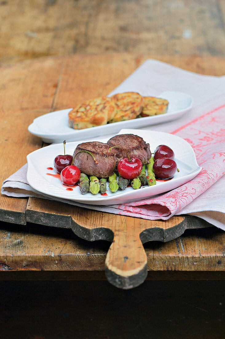 Venison medallions with glazed cherries and green asparagus