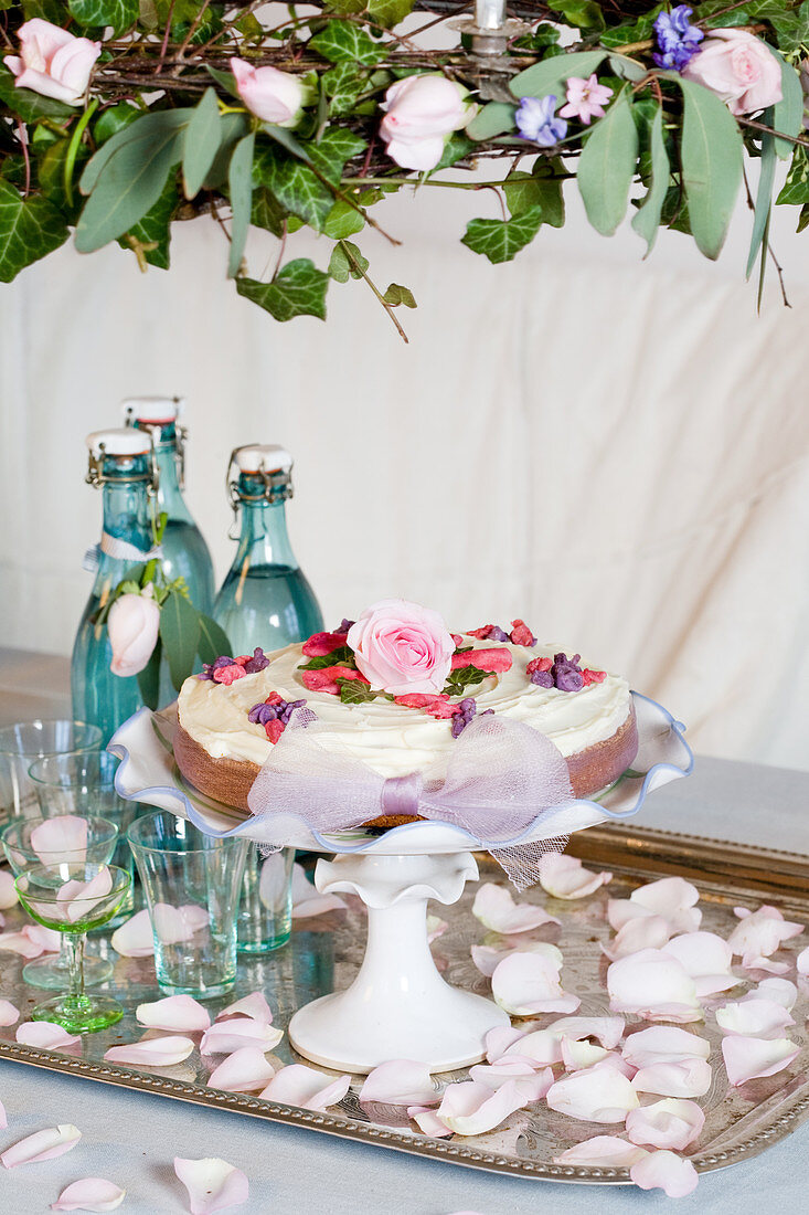 Torte mit Zuckerblumen auf einem Tablett unterm Blumenkranz