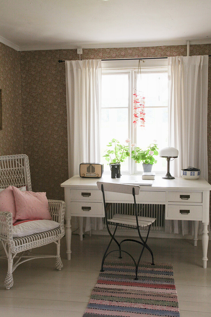 Korbstuhl, Gartenstuhl und weißer Schreibtisch am Fenster