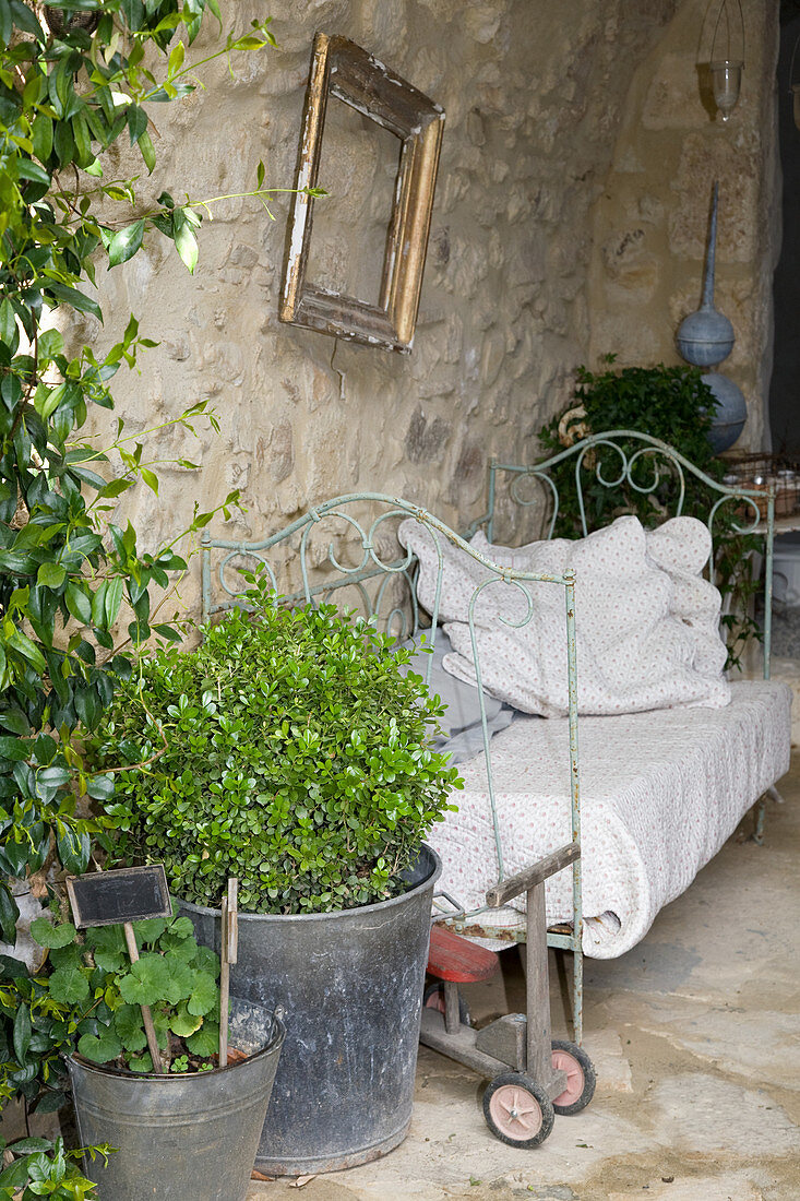 Altes Metallbett als Sofa im nostalgischen Innenhof mit Natursteinwand