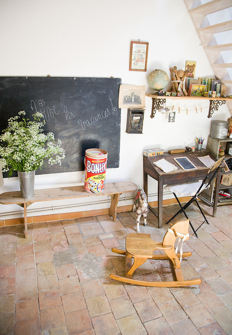 Rocking horse in front of an old bench, blackboard, and desk with junk as decoration