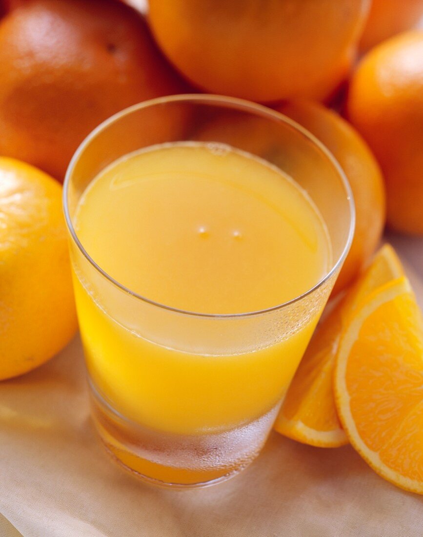 Ein Glas Orangensaft vor vielen frischen Orangen