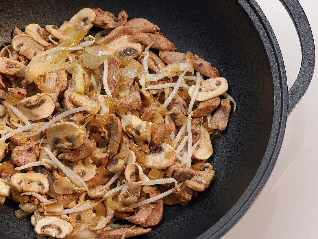 Stir-fried pork with mushrooms in a wok