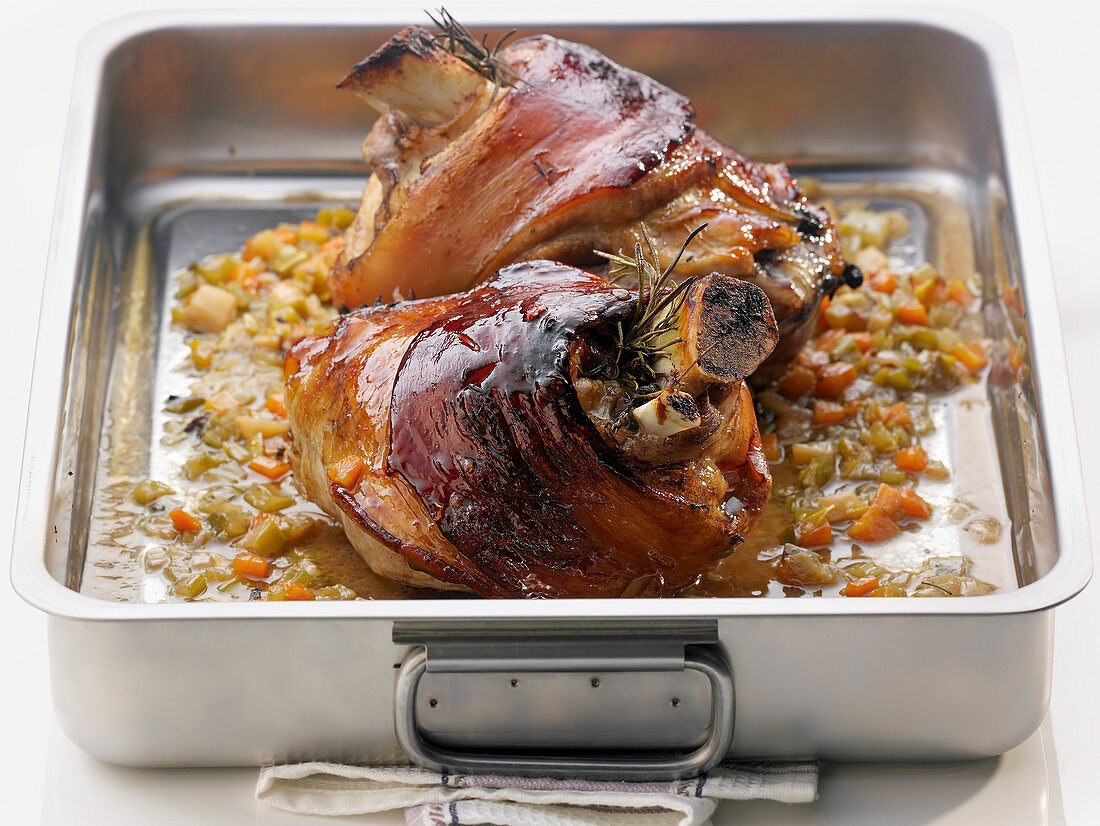 Pork knuckle with wheat beer and herbs in a roasting tin