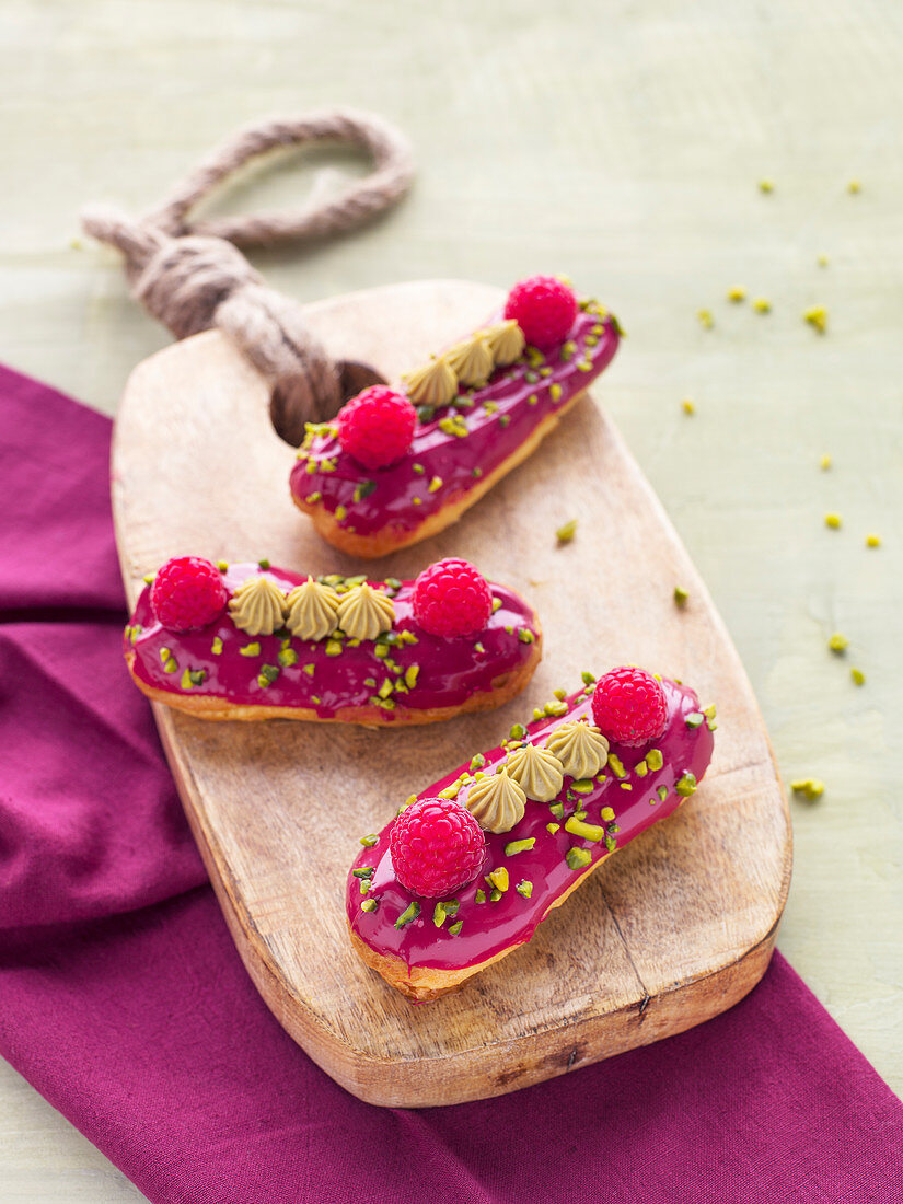 Himbeer-Eclairs mit Pistazien auf Holzbrett