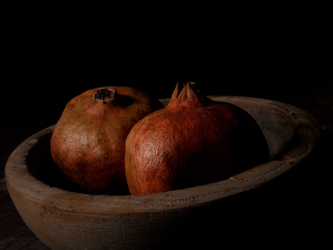Two pomegranates in a wooden bowl