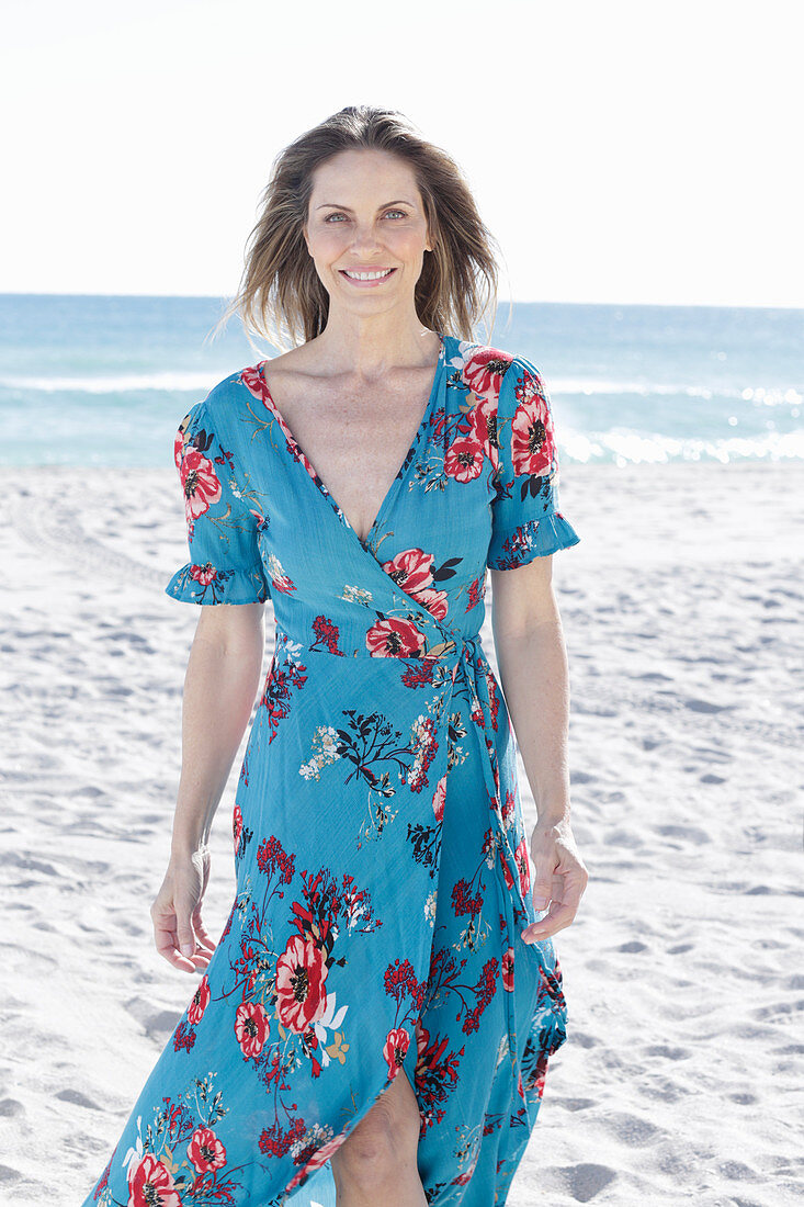 A long-haired woman on the beach wearing a summer dress