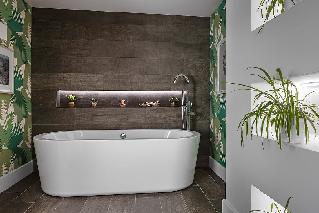 OVal bathtub in modern bathroom with houseplants in niches in wall