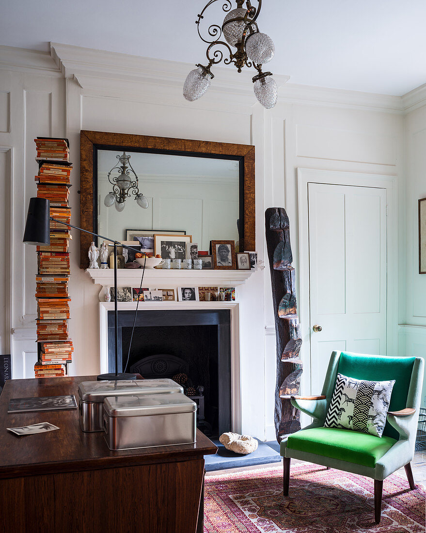 Green armchair in classic study with open fireplace