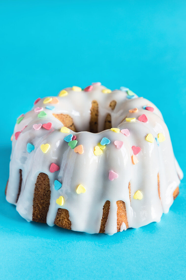 Bundt cake with icing and heart-shaped sugar sprinkles