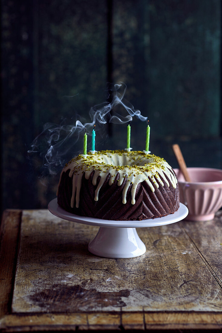Chocolate Bundt cake with a pistachio glaze and four blown-out candles