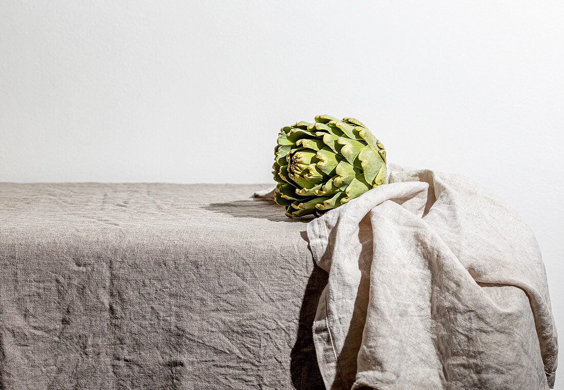 Artichoke on the table covered with a gray linen tablecloth