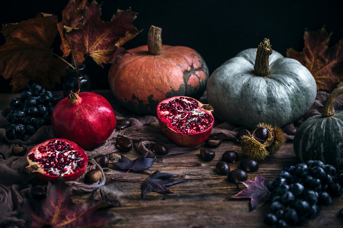 Herbststilleben mit Granatapfel, Kürbissen, Trauben und Kastanien