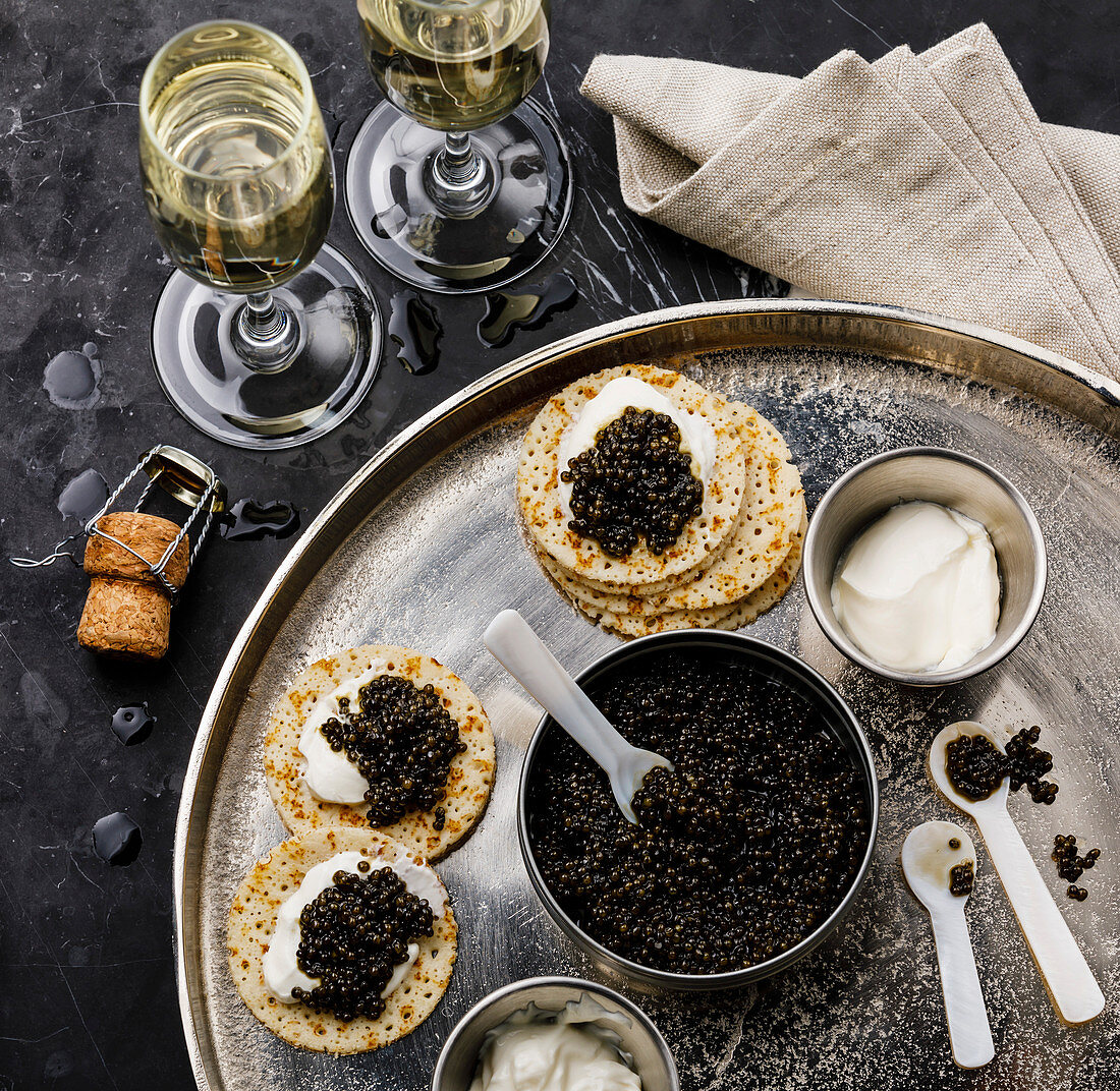 Black Caviar, Mini Pancakes and Sour Cream Holiday Party Appetizer on dark marble background