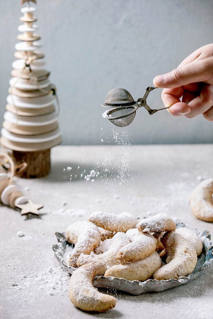 Homemade traditional Christmas shortcrust cookies vanilla crescents with icing sugar sprinkling from sieve