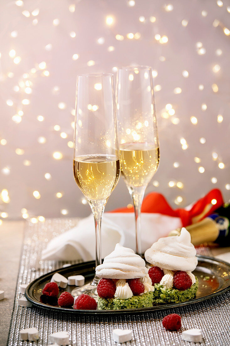 St. Valentine festive table setting with two Champagne glasses and berry meringue desserts