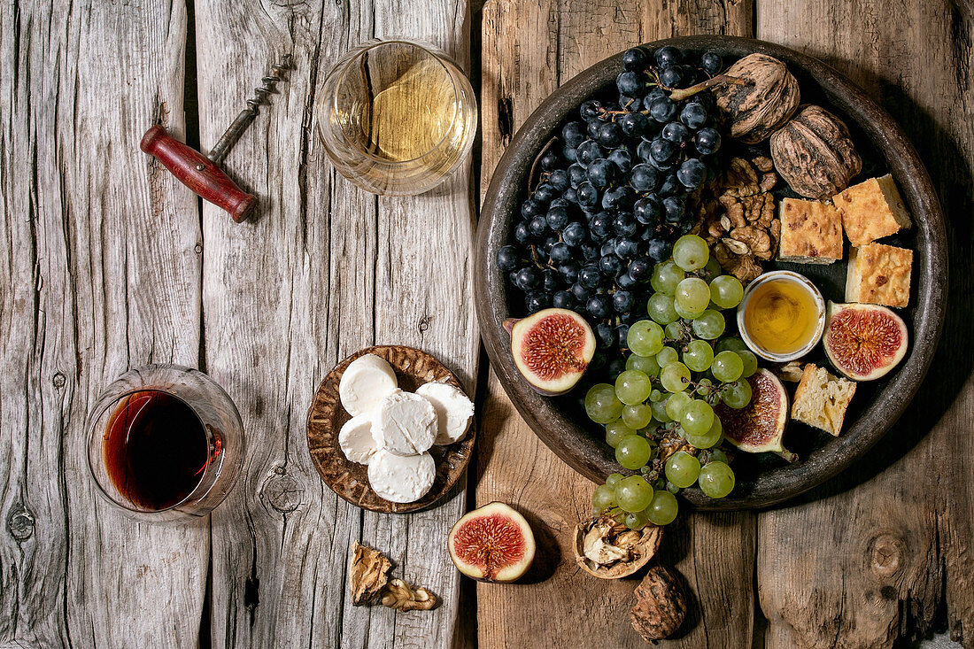 Wine appetizers with different grapes, figs, walnuts, bread, honey and goat cheese