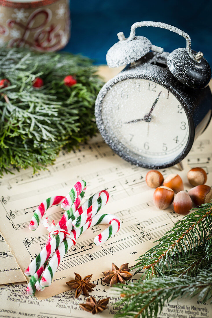 Candy canes, hazelnuts and alarm clock on music sheet
