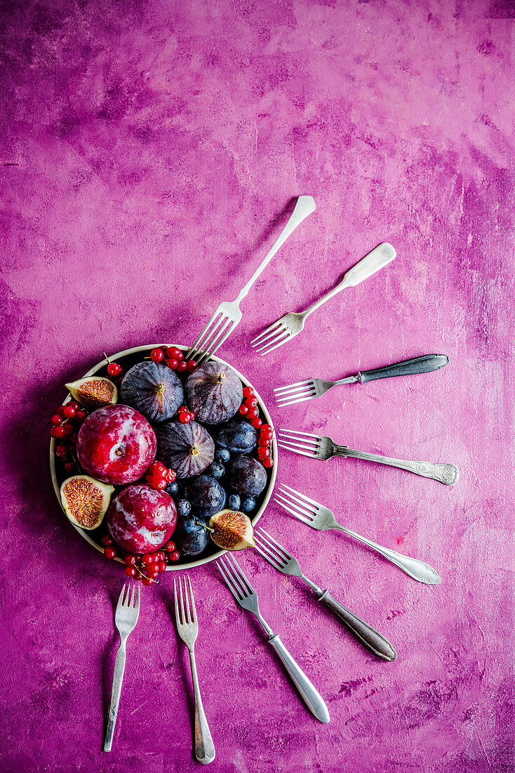 Frische Pflaumen, Feigen und Beeren in Schälchen mit Gabeln