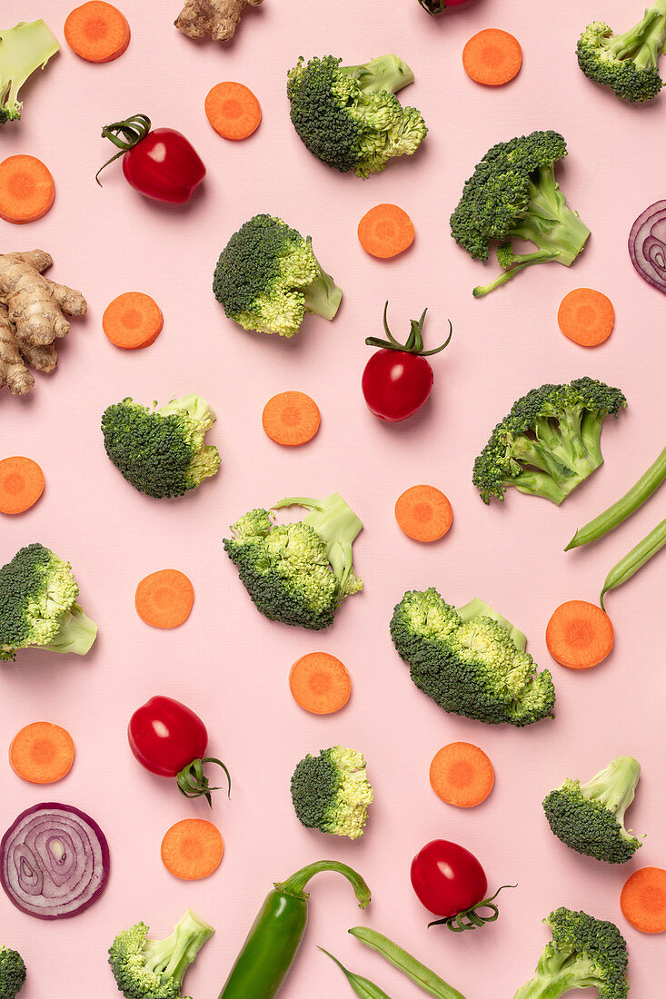 Tomaten, Brokkoli, Karotten, Ingwer und Zwiebel auf rosa Hintergrund