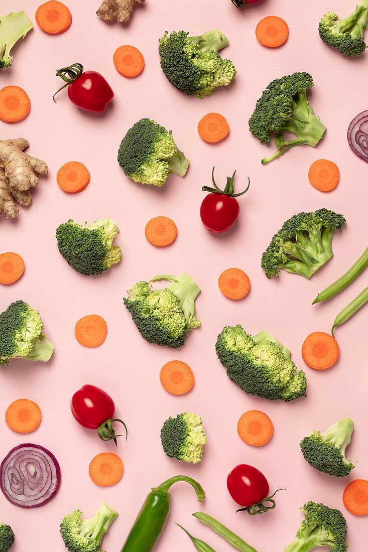 Tomatoes, broccoli, carrots, ginger and onion on pink background