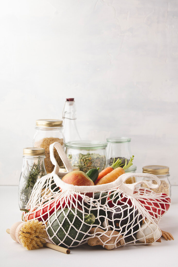 Fruits and vegetables in reusable bags and glass jars with pasta, lentils, beans, rice, dry herbs