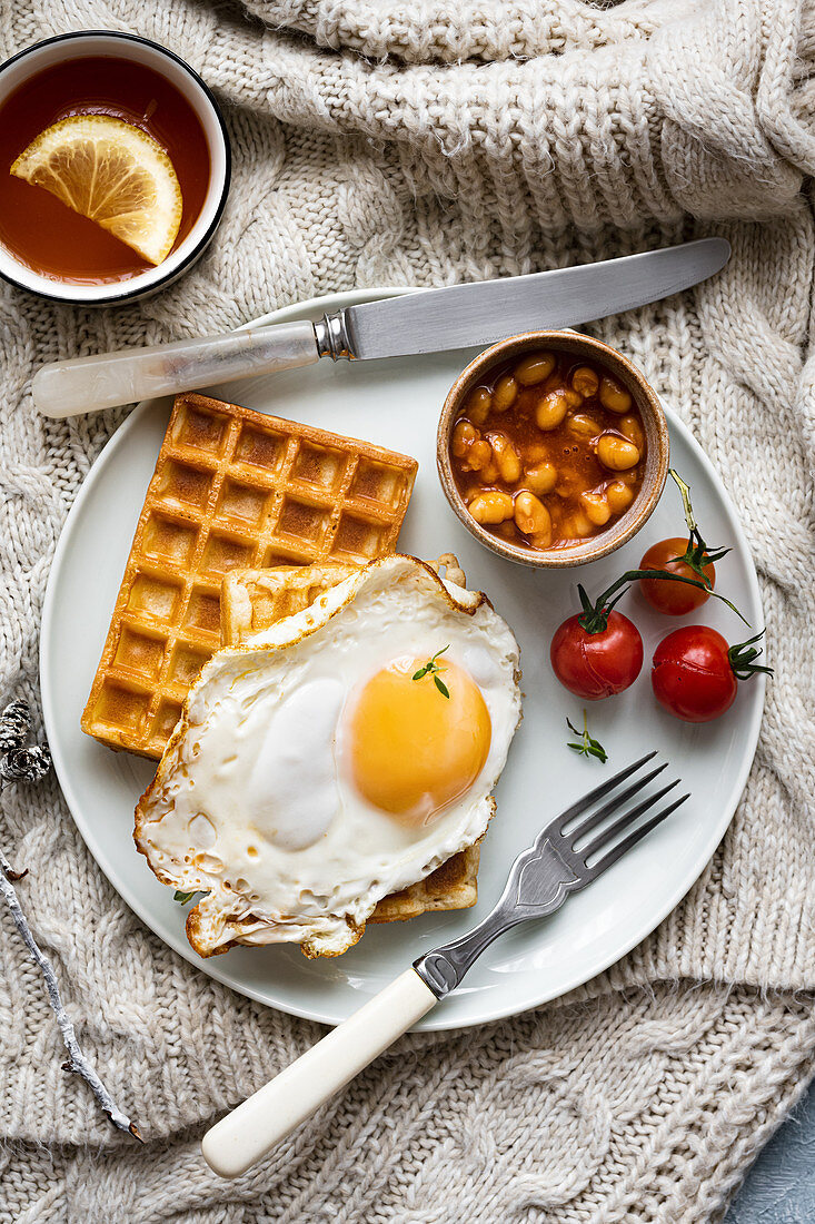 Breakfast with fried egg, baked beans and waffles