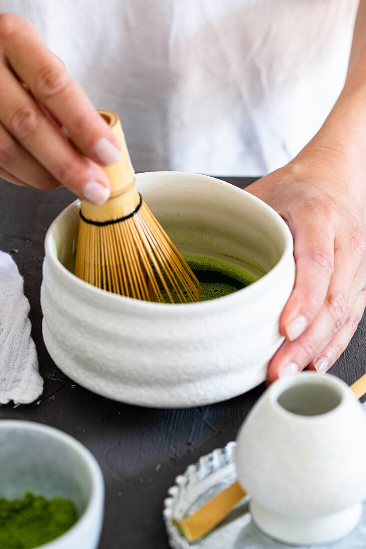Whipping matcha tea with a bamboo whisk