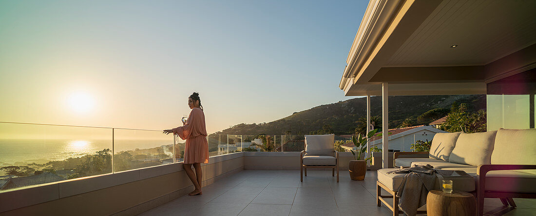 Woman with white wine enjoying sunset ocean view