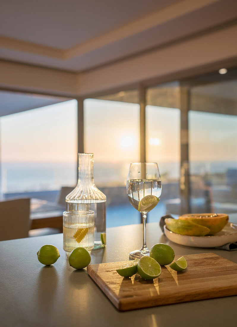 Water and fresh limes on kitchen counter at sunset
