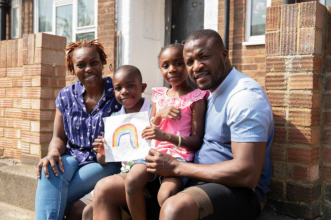 Portrait family with rainbow drawing on front stoop