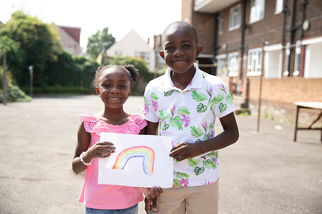 Brother and sister holding rainbow drawing outside