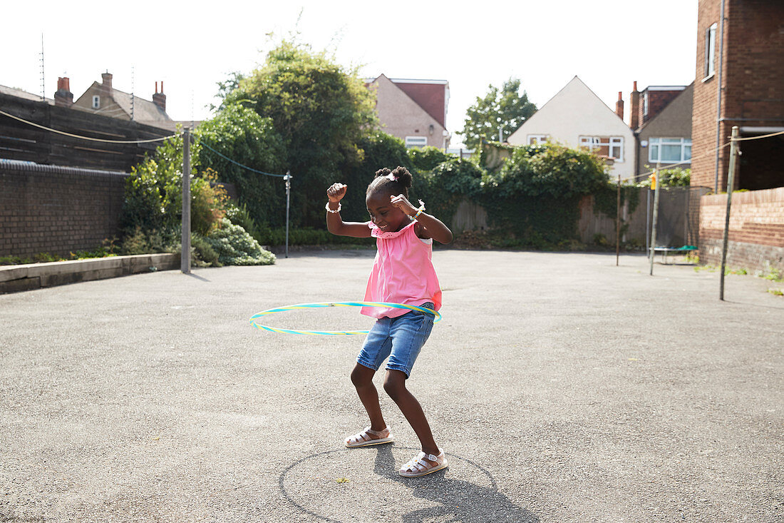 Playful girl spinning in plastic hoop in neighbourhood