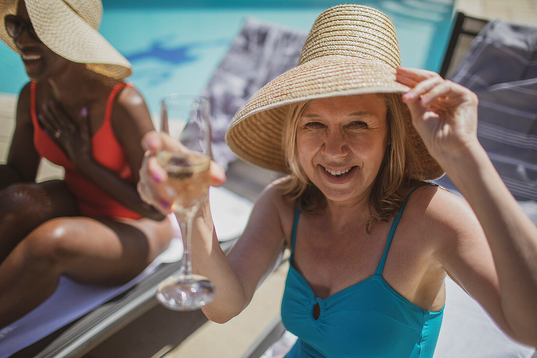 Portrait senior woman drinking champagne at poolside