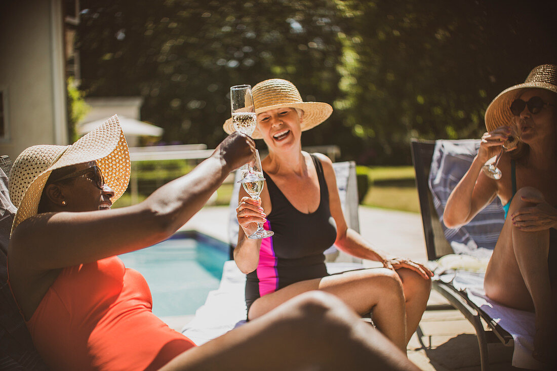 Senior women friends toasting champagne at poolside