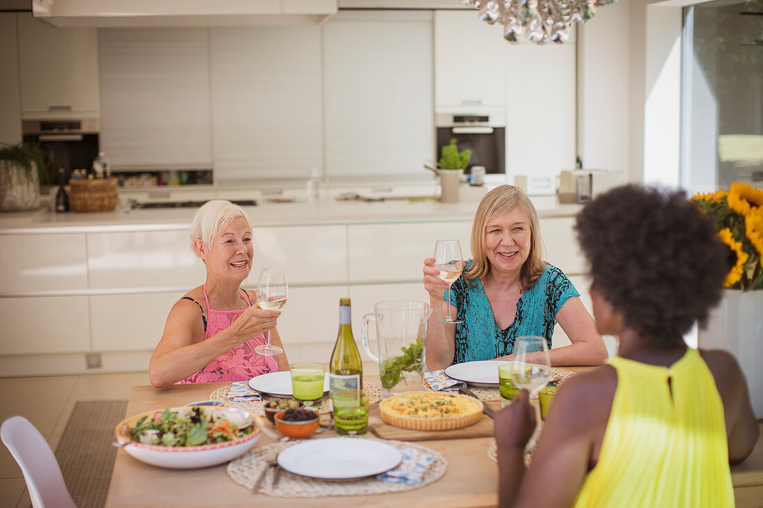 Senior women friends enjoying white wine with lunch
