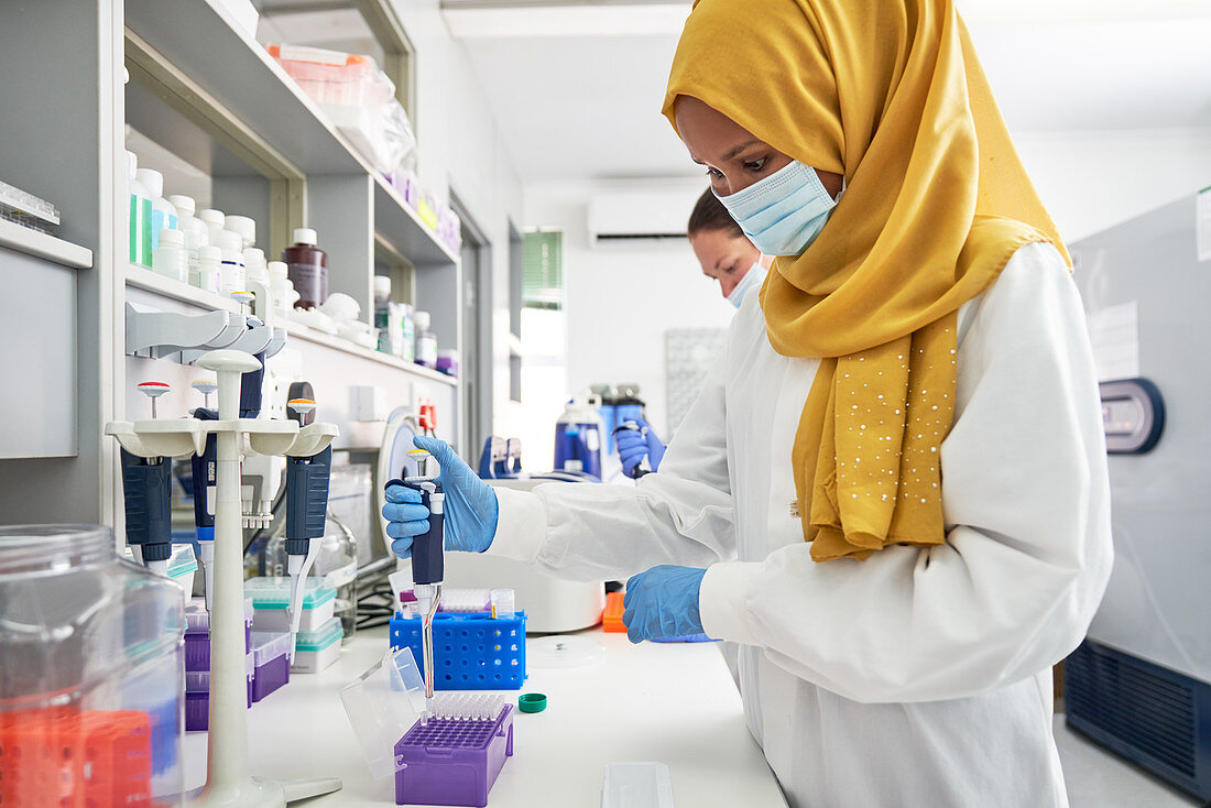 Scientist in hijab and face mask using pipette