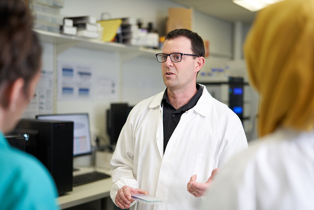 Male scientist talking with colleagues in laboratory