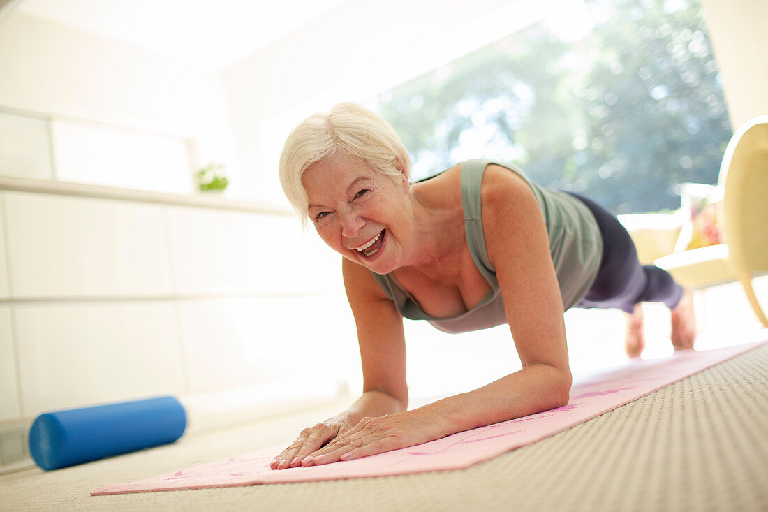 Senior woman practicing plank pose at home