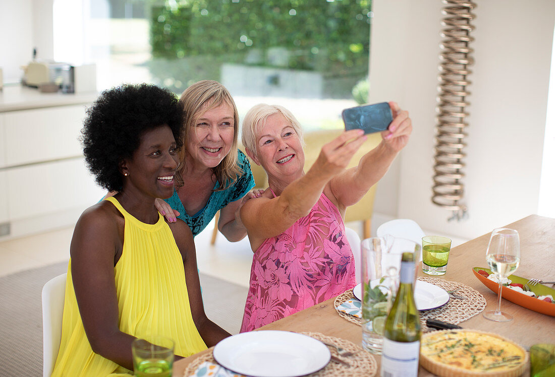 Happy senior women friends taking selfie at luncheon