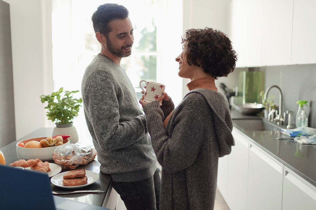Happy couple talking in morning kitchen