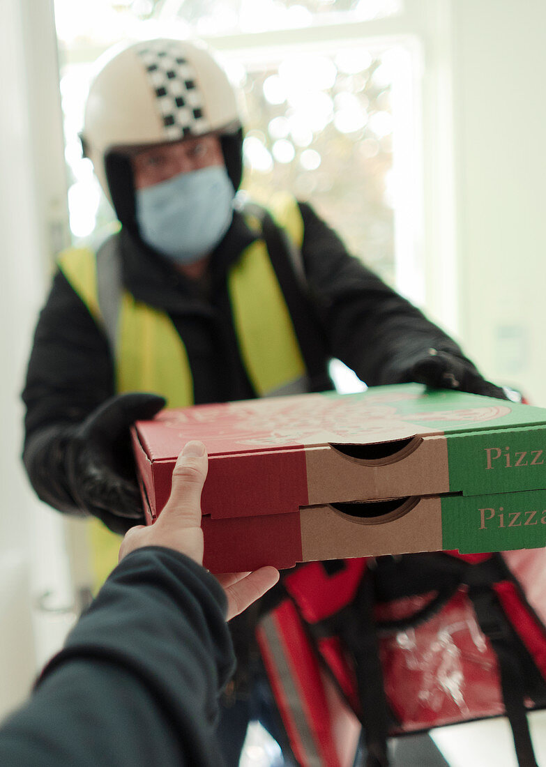 Man in face mask and helmet delivering pizza