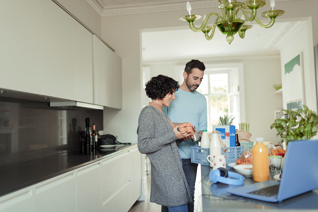 Couple unloading grocery delivery at kitchen counter