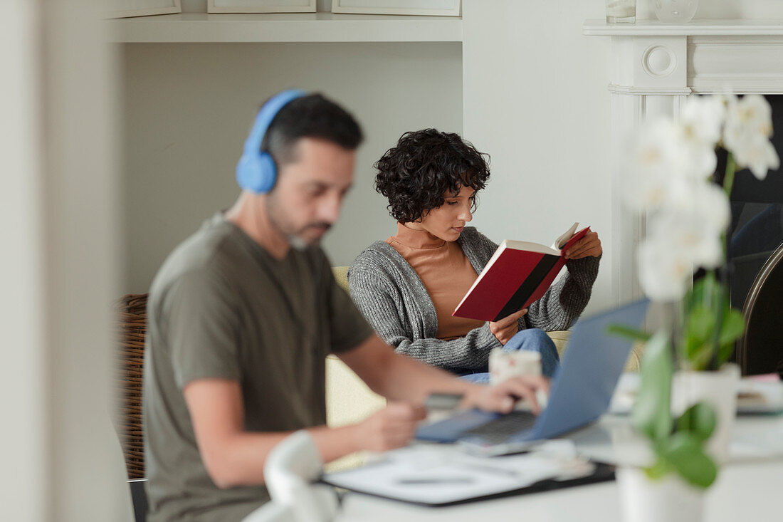 Couple reading and working from home at laptop