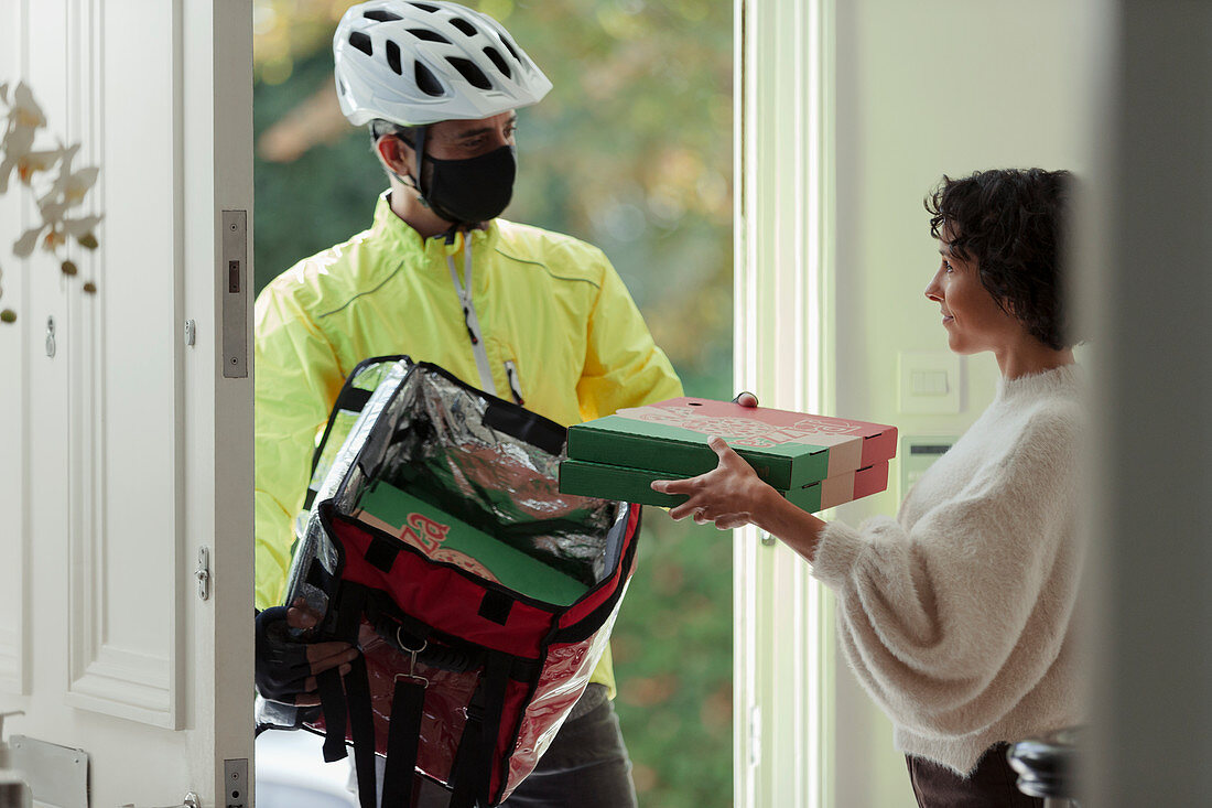 Woman receiving pizza delivery in face mask