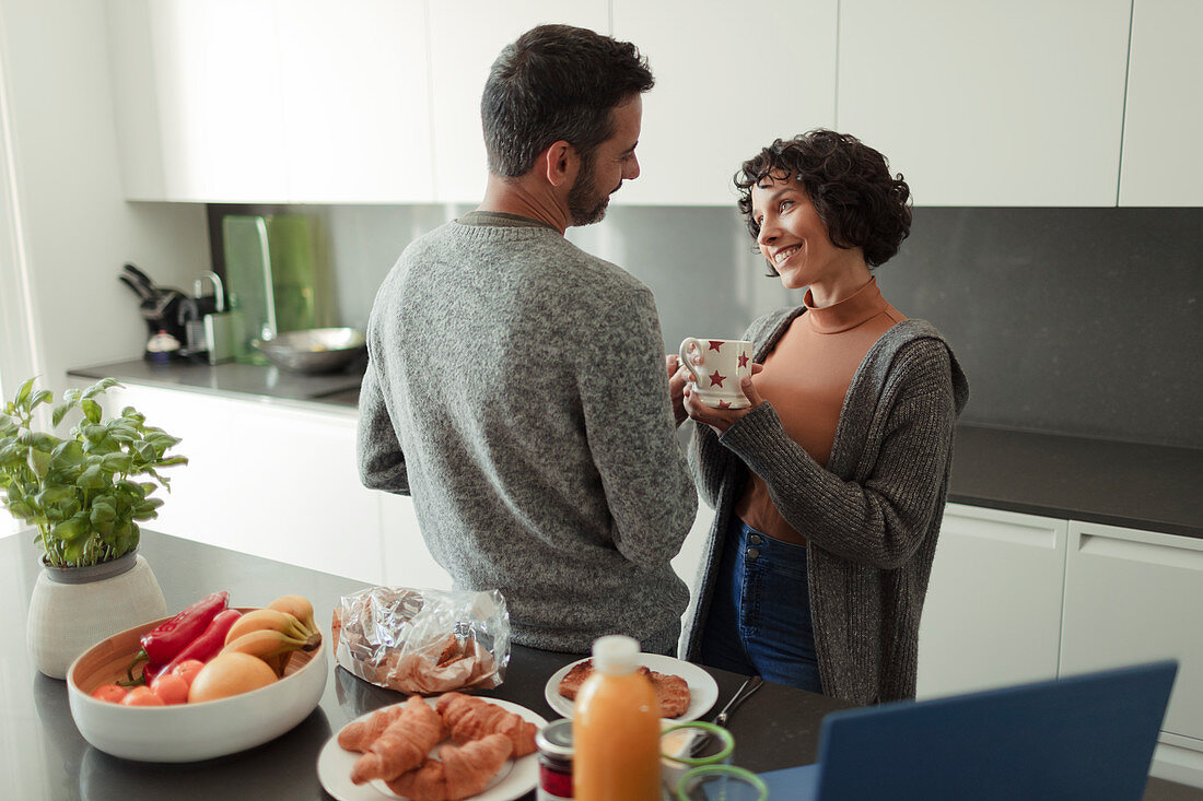 Couple enjoying breakfast and coffee in morning kitchen