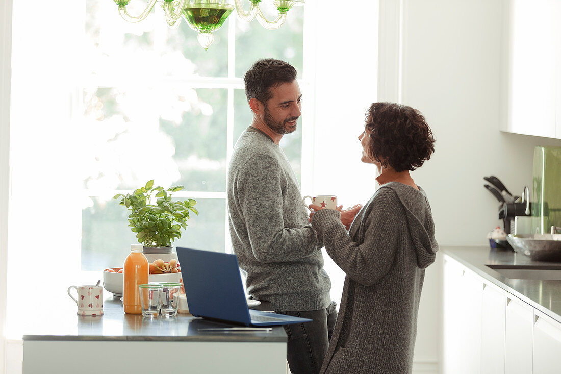 Happy couple talking and working in morning kitchen