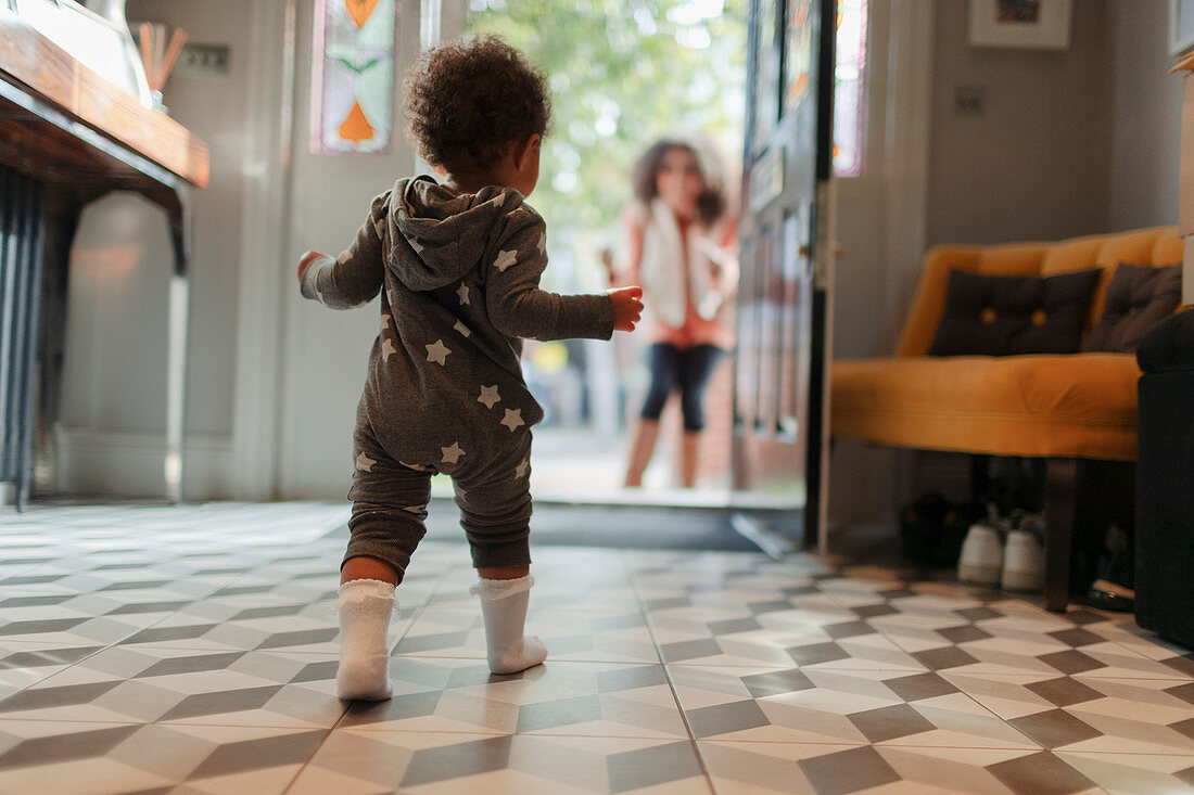 Cute baby girl in star pyjamas walking to mother