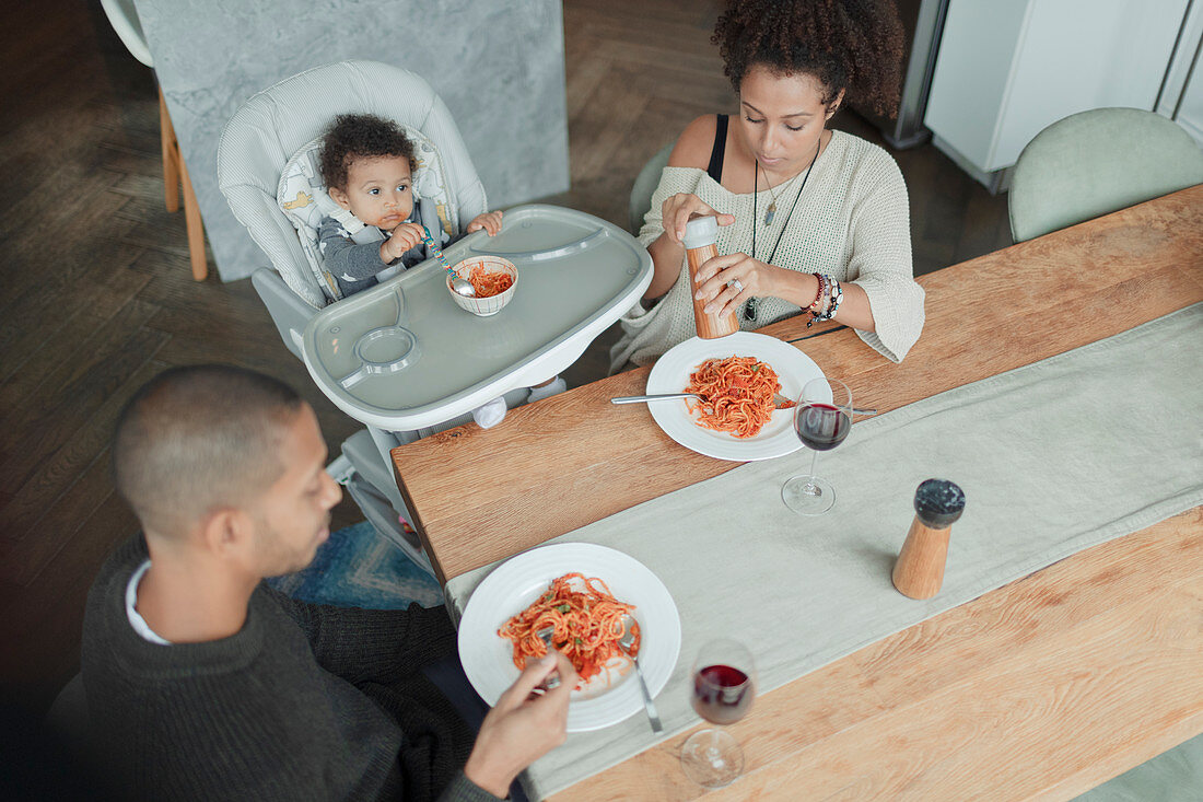 Family eating spaghetti at dining table and high chair